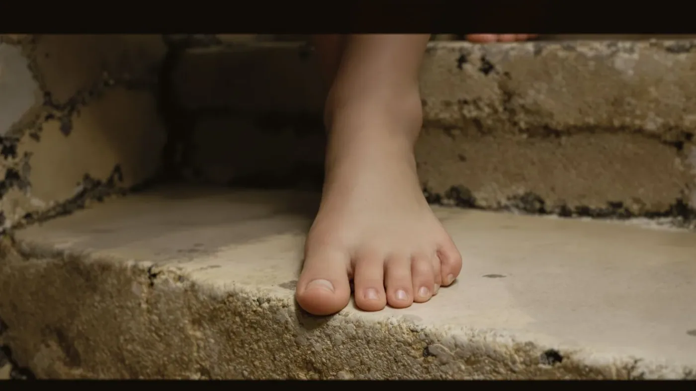 Bare feet on stone steps in natural light showing the body creating emotional safety one step at a time