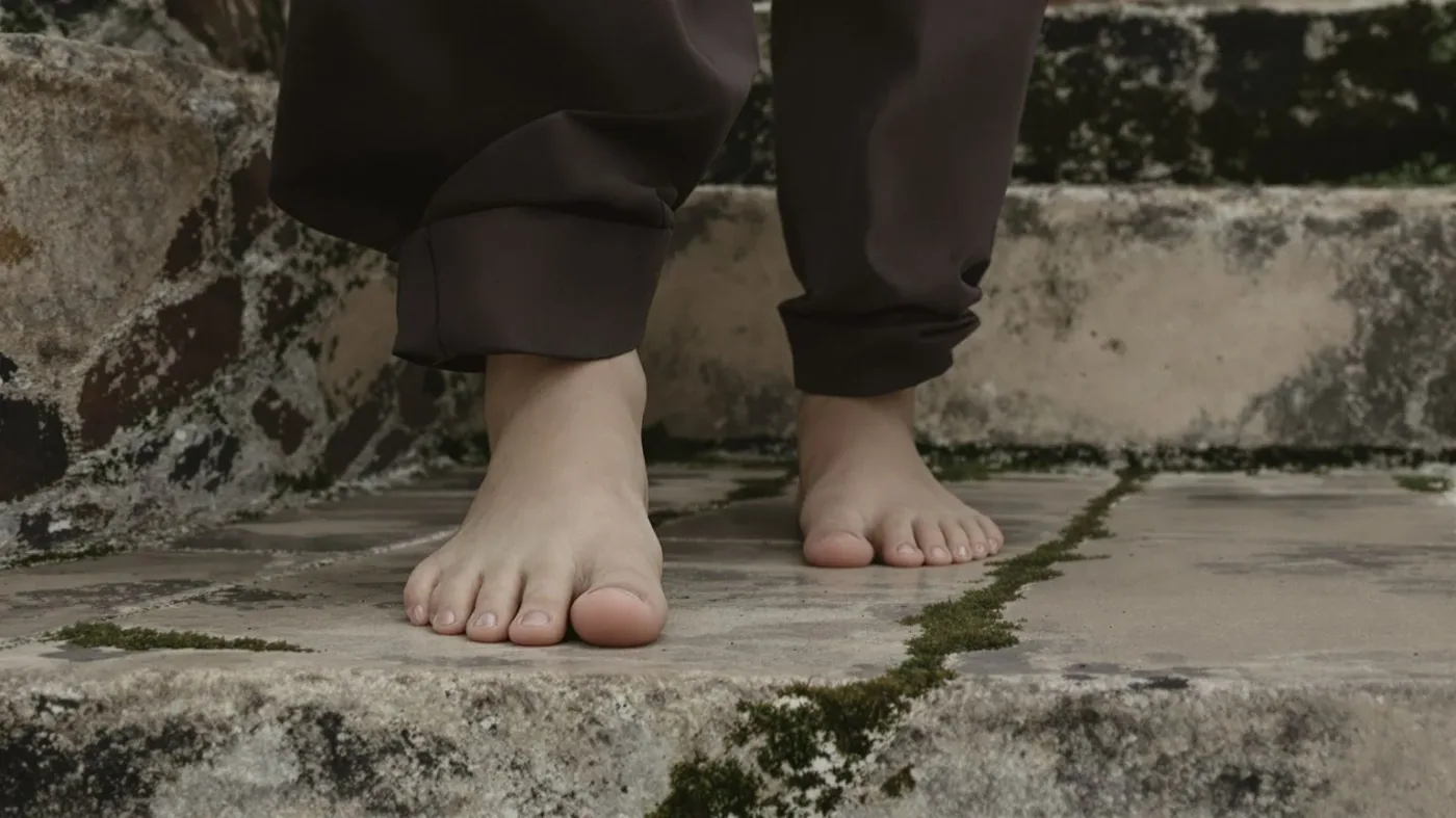 Bare feet on worn stone steps representing a body-first practice for emotional masking recovery