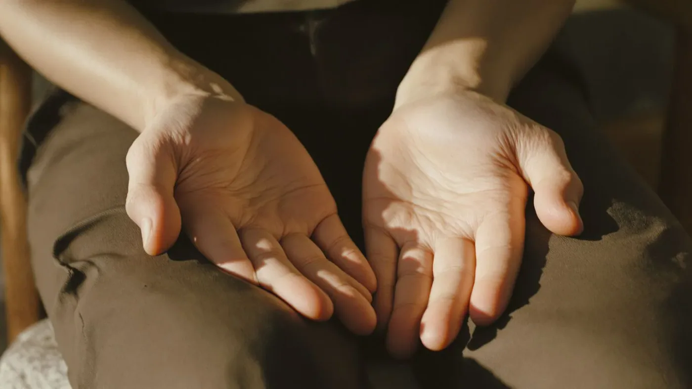 Close-up of hands resting on thighs showing body awareness during emotional exhaustion recovery