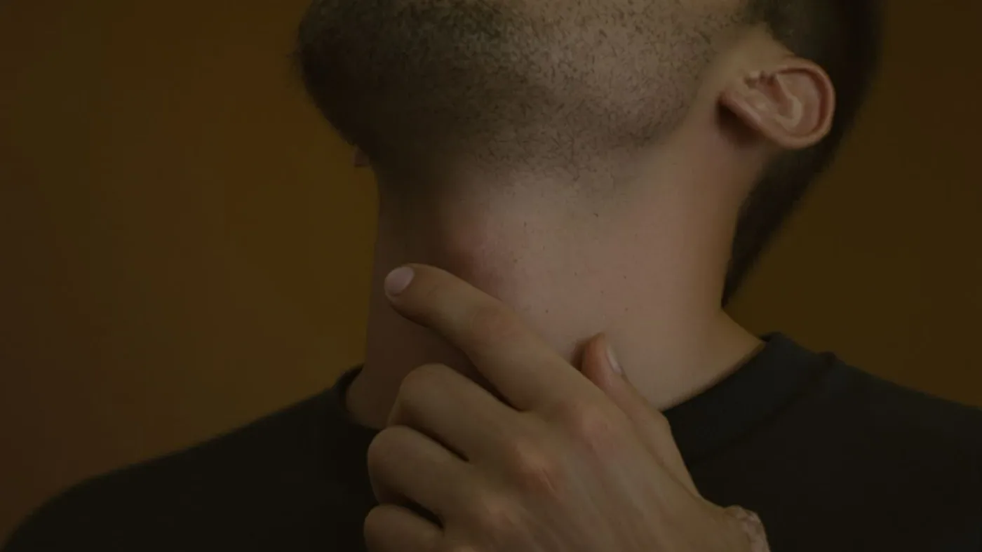 Close-up of man's hand near throat and neck showing body tension when mind says nobody cares