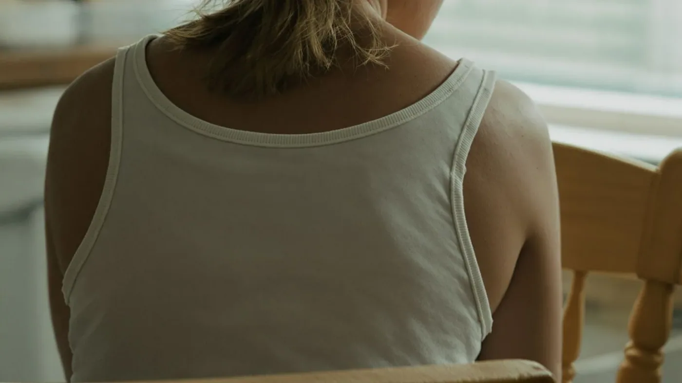 Close-up of tense shoulders and curved back showing recurring tension between massage sessions
