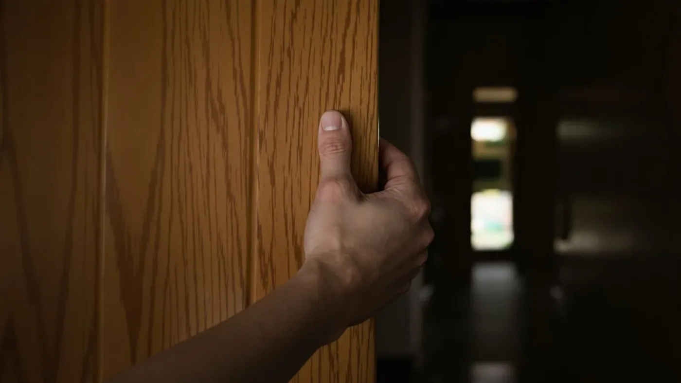Hand gripping a doorframe threshold, body tension visible in knuckles, improving emotional intimacy in real moments