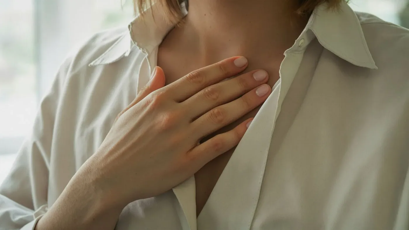 Hand pressed against sternum over linen shirt showing what feeling alone in a relationship feels like in the body