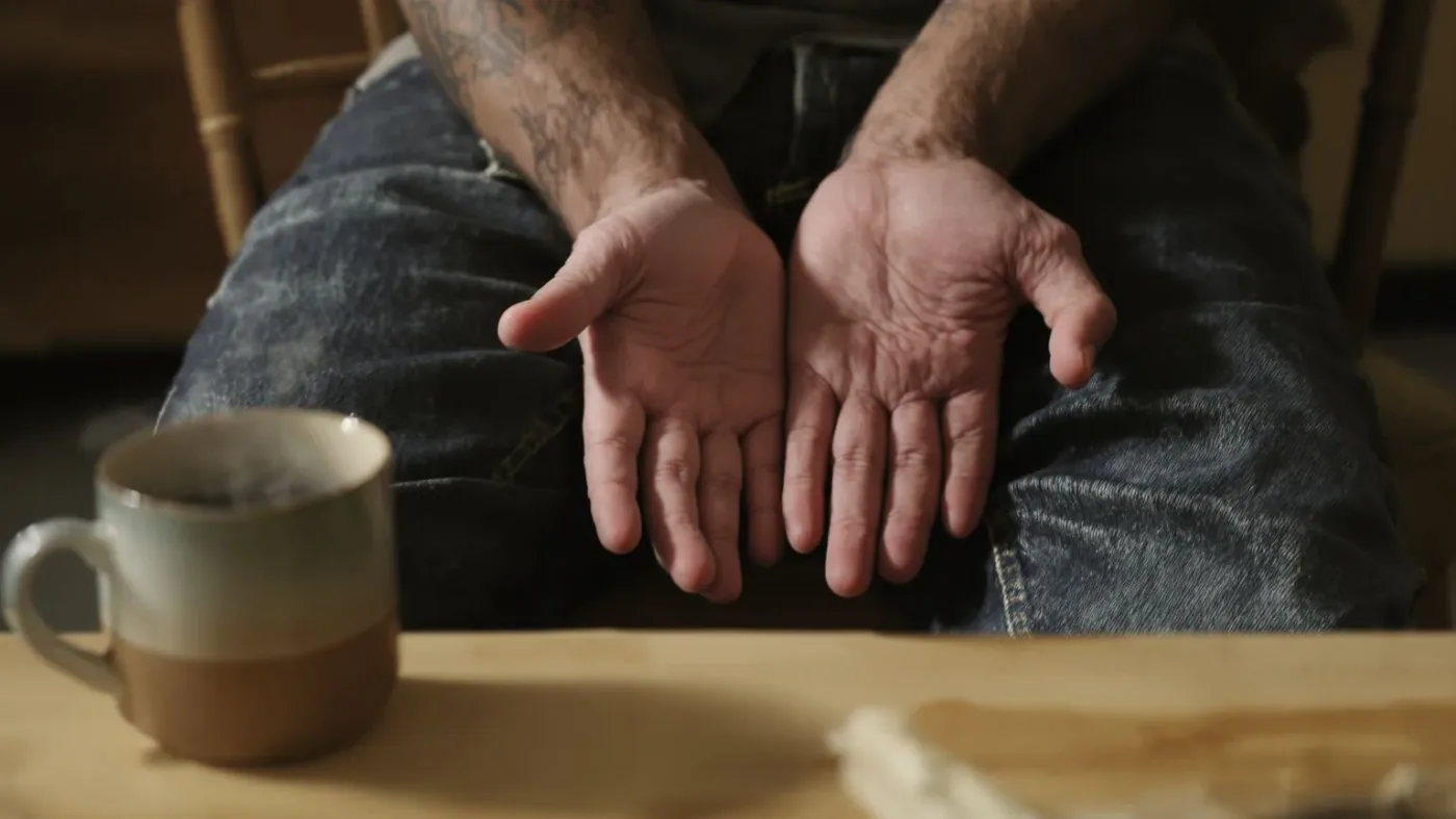 Hands resting on lap near ceramic mug showing what softened after emotional release technique