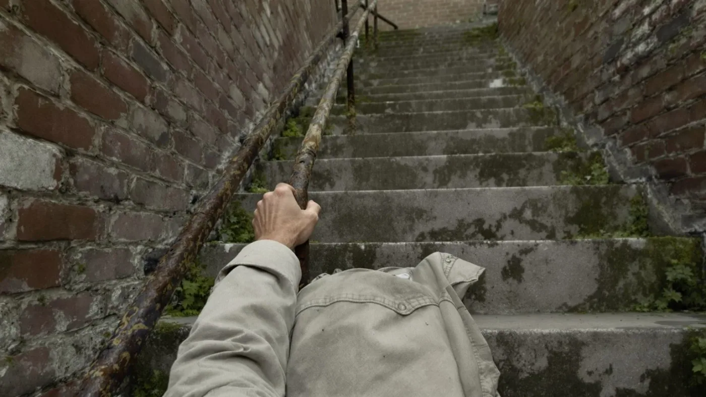 Man climbing worn concrete steps with tense grip on railing showing how suppression scrambles memory physically