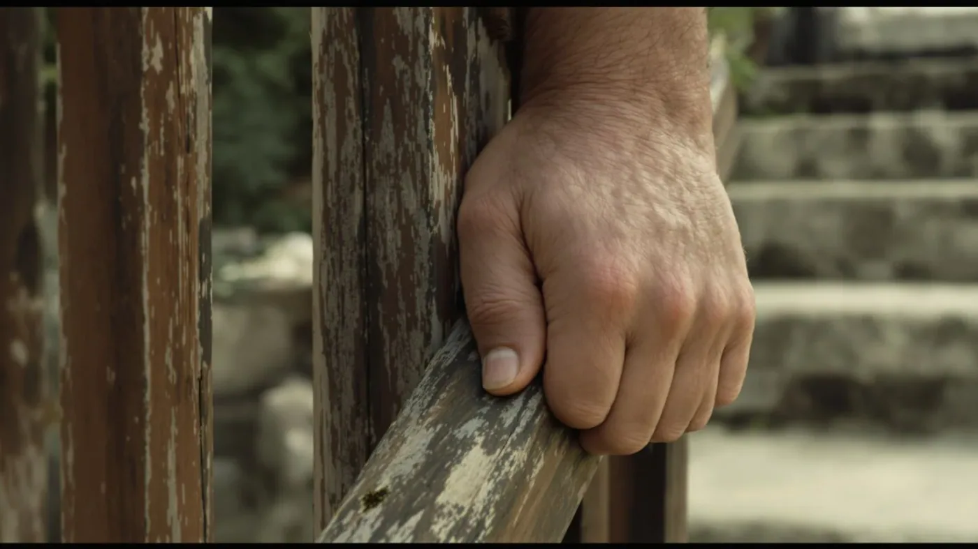 Man's tense hands gripping a wooden stair railing, showing how the body knows before memory does