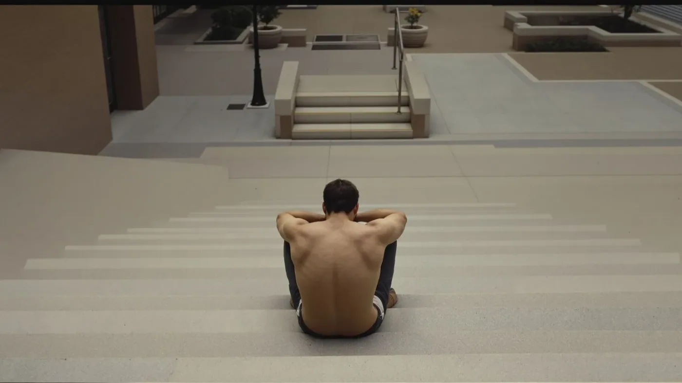 Man sitting on concrete steps with heavy posture reflecting the weight of searching for somatic exercises to release trauma
