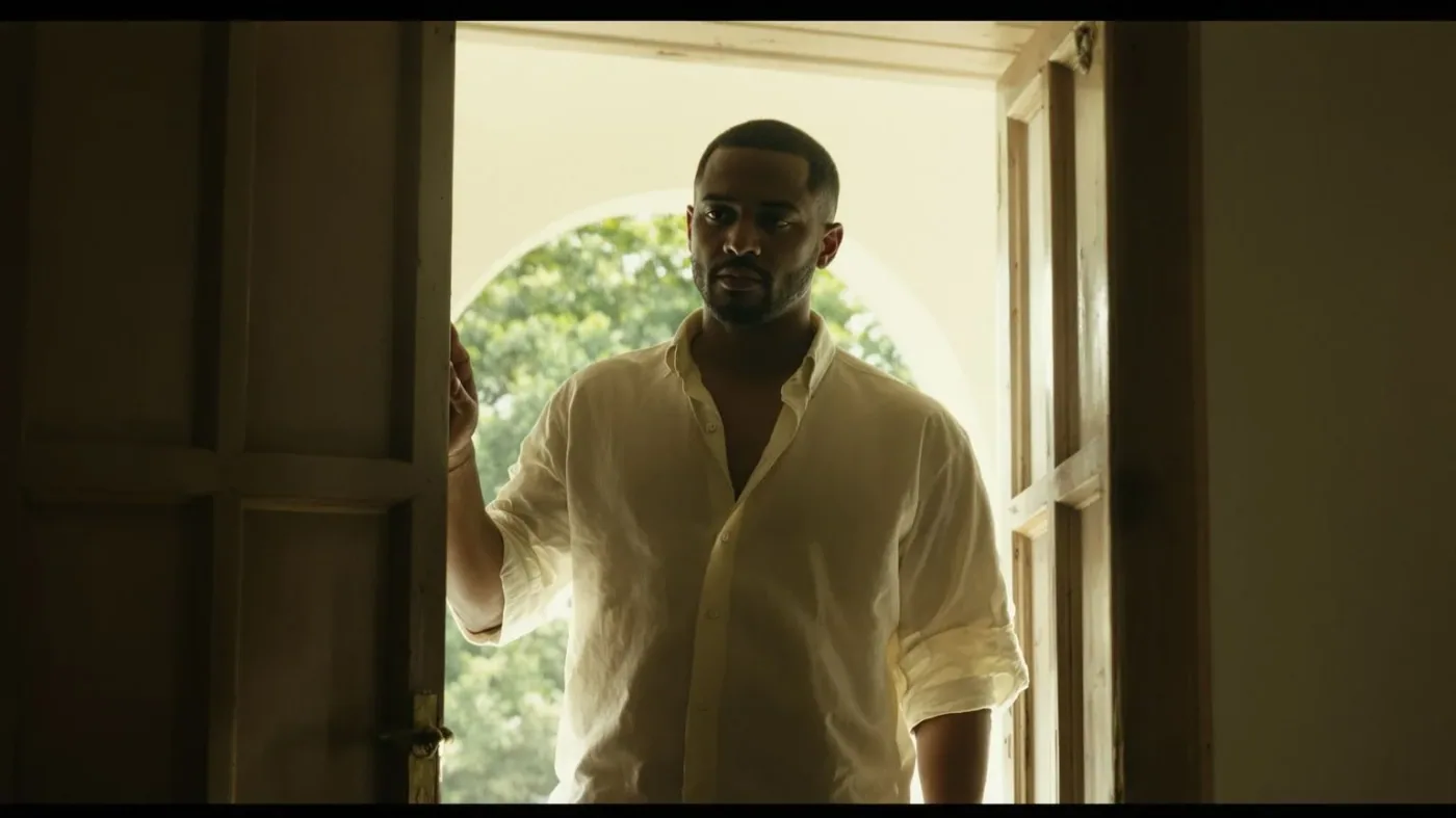 Man standing at a sunlit doorway threshold, body half in shadow, showing what shifts after emotional practice