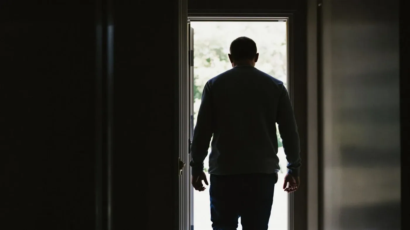 Man walking through an open doorway into morning light, taking the clear next step toward emotional openness
