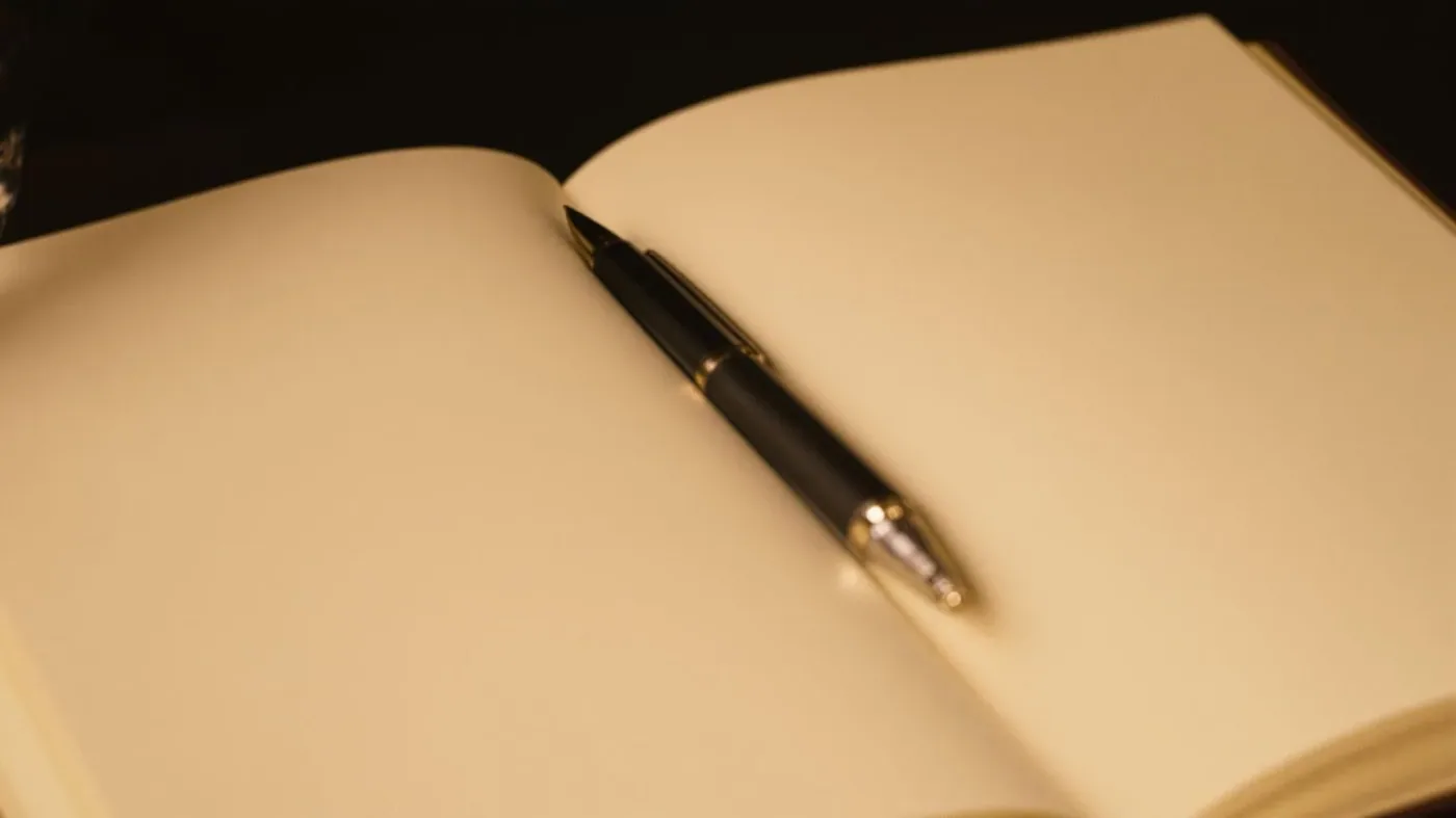 Open blank notebook and pen on nightstand representing emotional suppression effects on memory