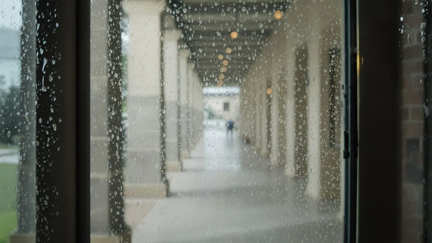 Rain-streaked window blurring a corridor beyond showing why memory fog happens when containing emotions
