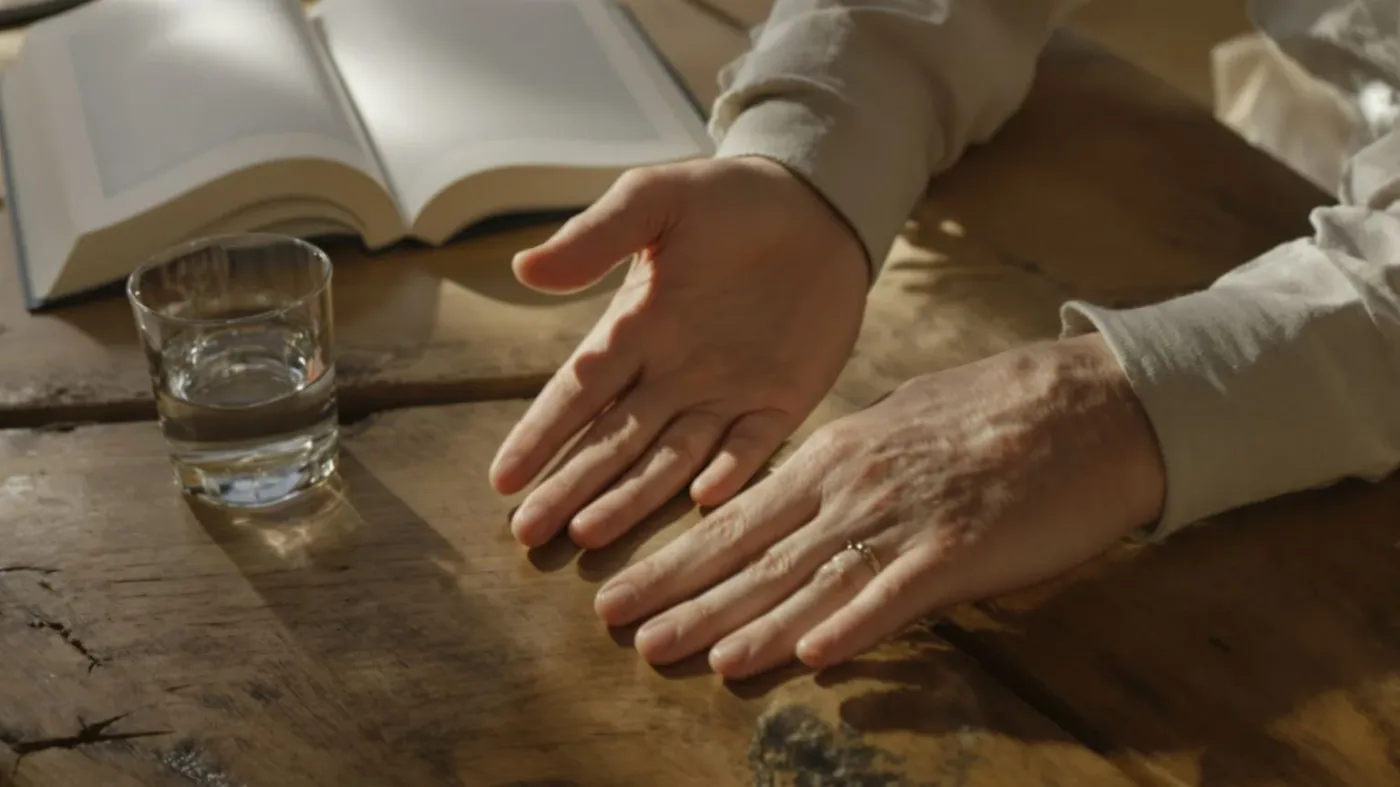 Relaxed hands resting on wooden table beside open journal showing what shifts after emotional safety practice