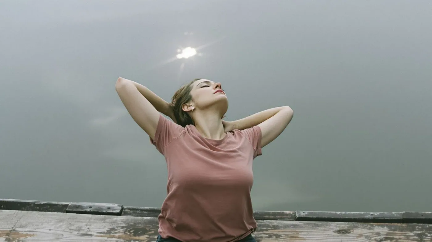 Woman leaning back on a dock with open chest breathing freely, showing what changes before anything is fixed
