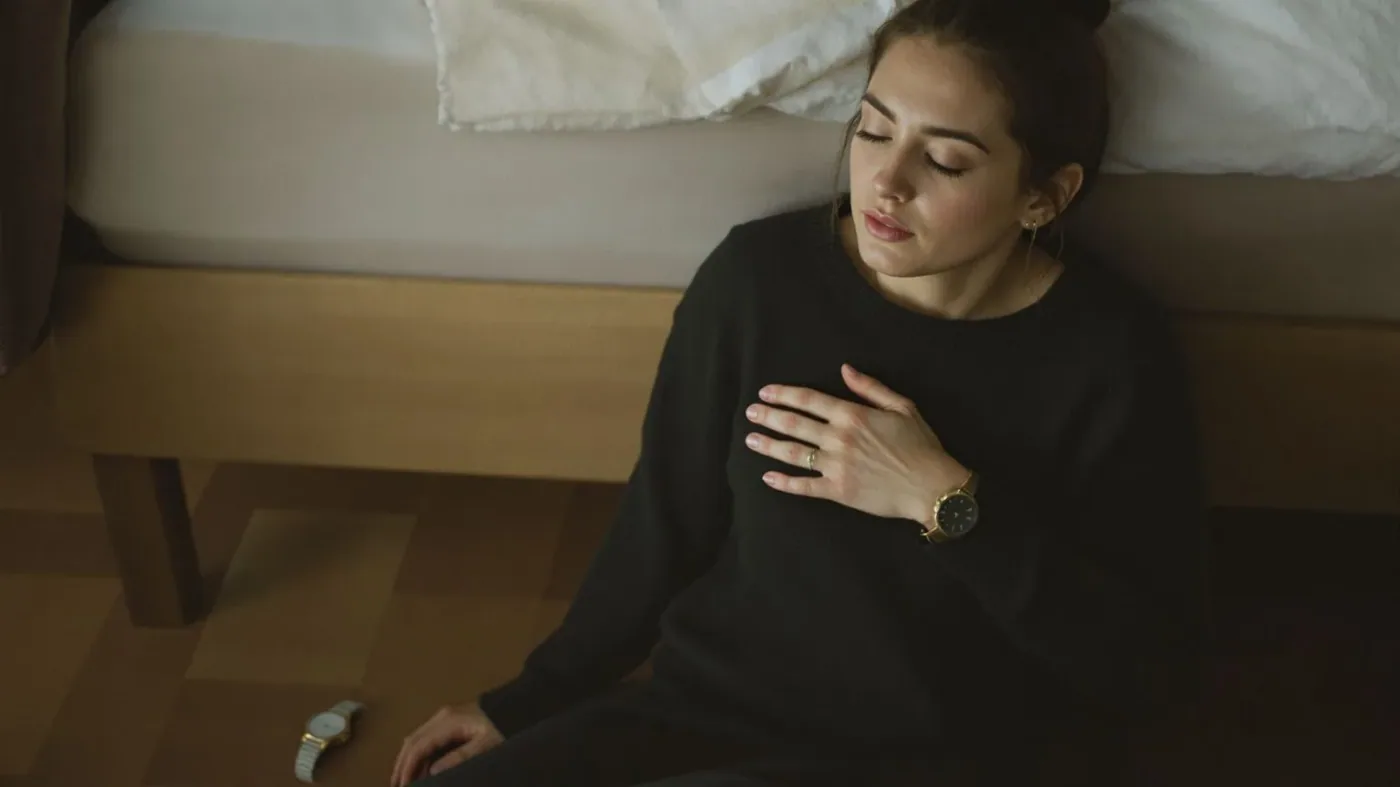 Woman sitting on floor with hand on chest during a 12-minute emotional reset to stop shutting down