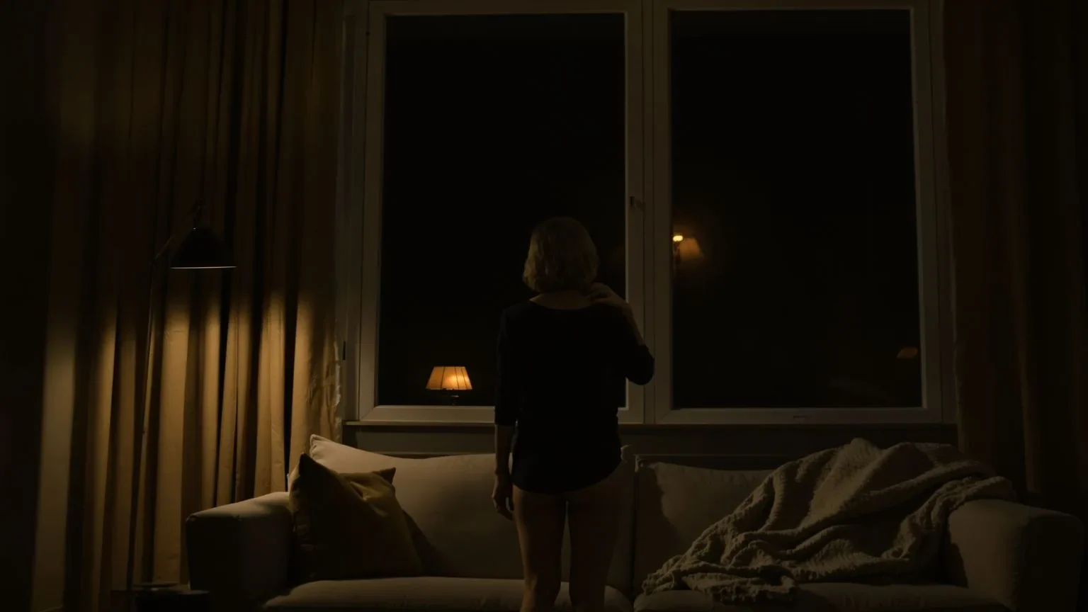 Woman standing alone at night in living room touching her collarbone after kristin neff self compassion meditations