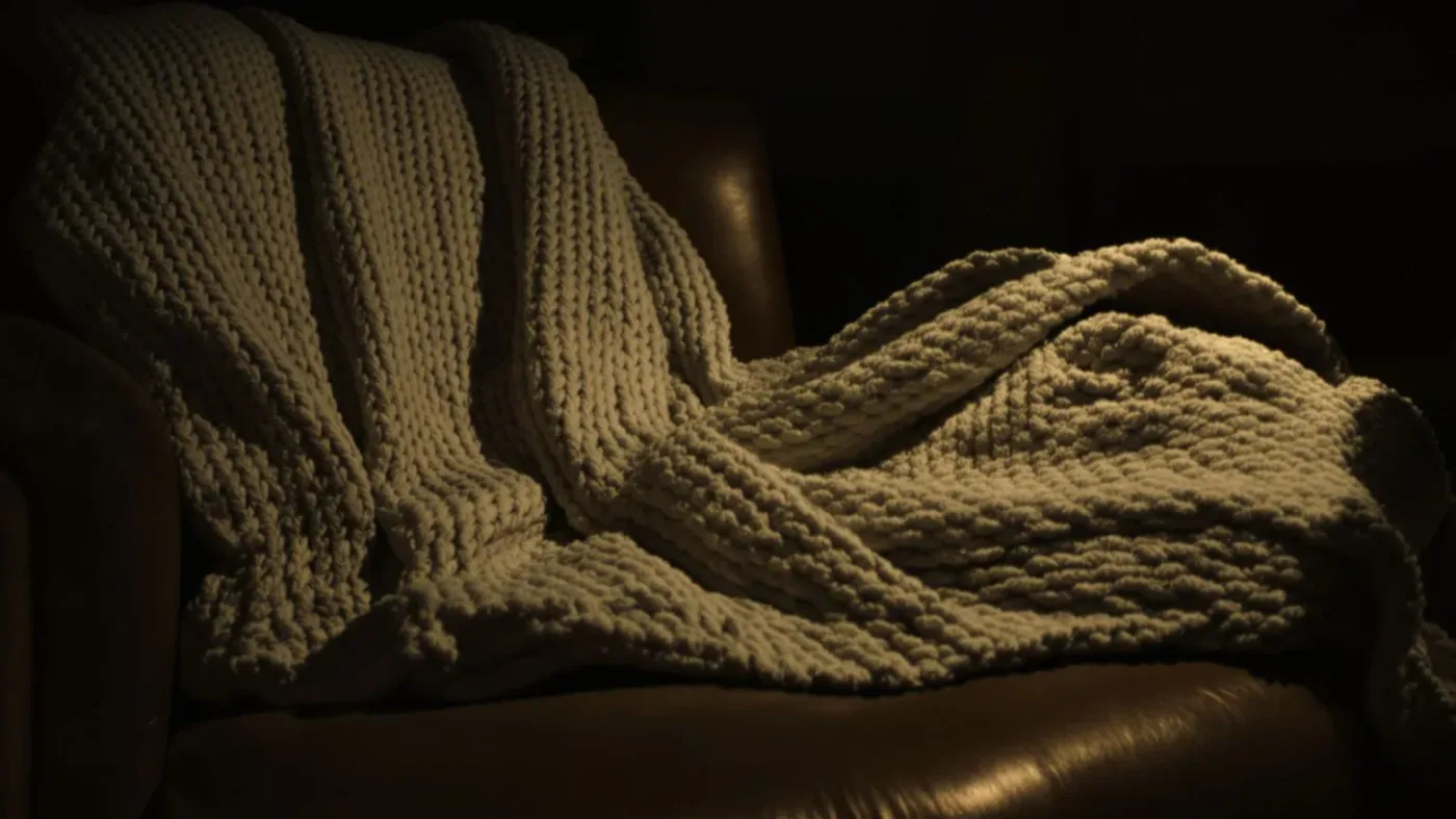 Wool blanket draped on armchair with body impression showing protective comfort not brokenness